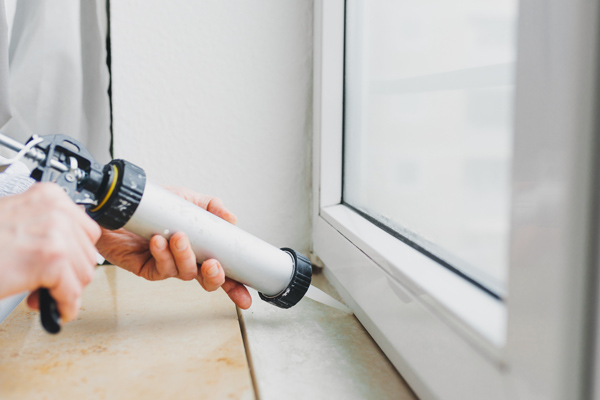 image of a man caulking window to prevent air leaks