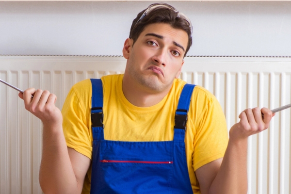HVAC technician shrugging while holding tools depicting HVAC failure