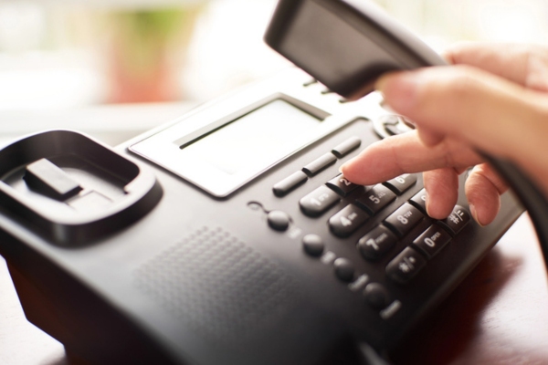 woman's hand dialing on a home phone depicting When to Contact an HVAC Professional