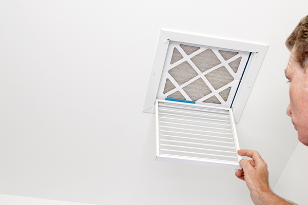 image of a man looking at hvac air vent and air filter