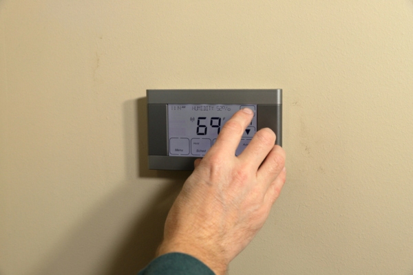 homeowner controlling digital home thermostat