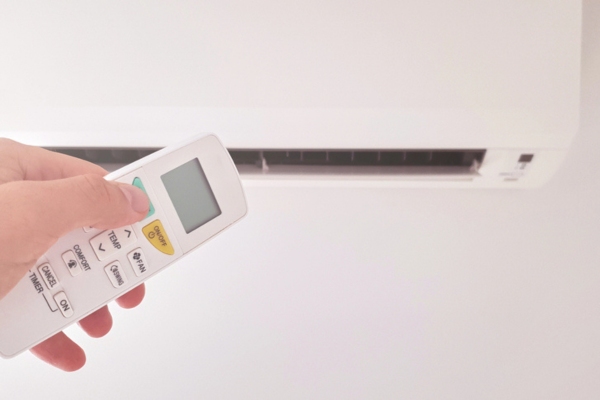modern ductless HVAC system with hand holding remote