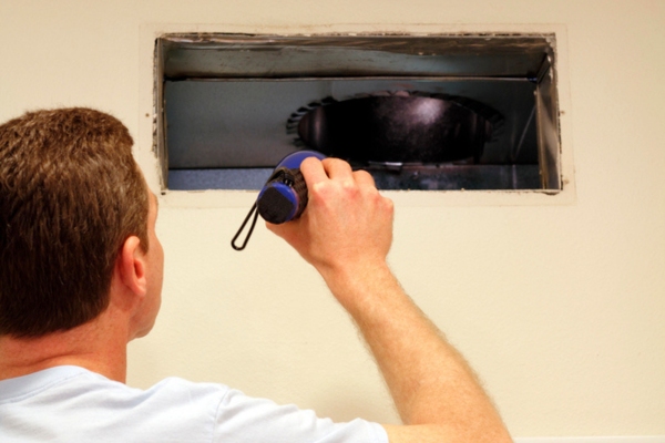 homeowner checking HVAC ductwork depicting thumping or popping sounds