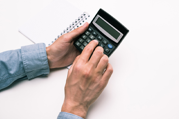 hands with calculator and notepad depicting seasonal energy efficiency rating of an air conditioning system