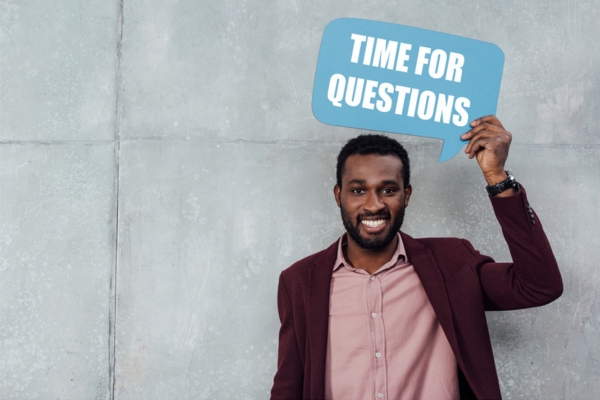 man holding a speech bubble cutout sign that says time for questions depicting FAQS about Heating Efficiency