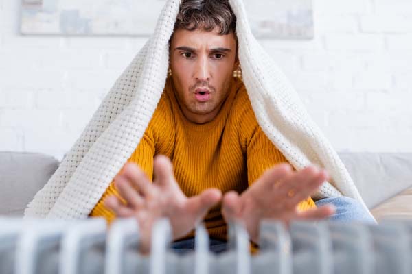 image of a homeowner in front of space heater depicting running out of home heating oil