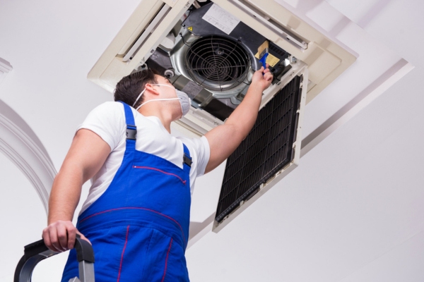 Professional worker cleaning ceiling indoor AC unit
