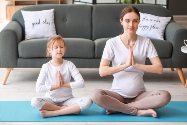 pregnant mom and young daughter practicing indoor yoga