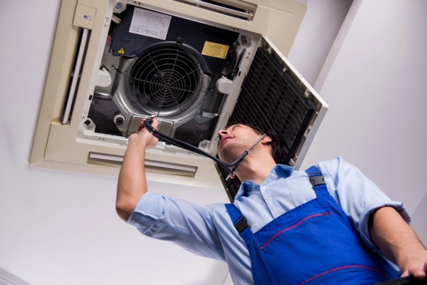 HVAC technician repairing ceiling air conditioning unit