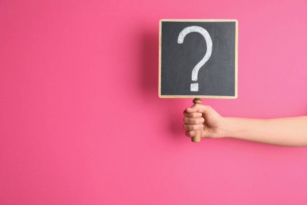 question mark on a sign held up by a woman's hand depicting FAQs About AC Installation