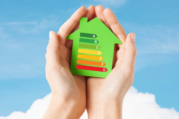hands holding green paper house with energy efficiency chart depicting AFUE vs AFUE2