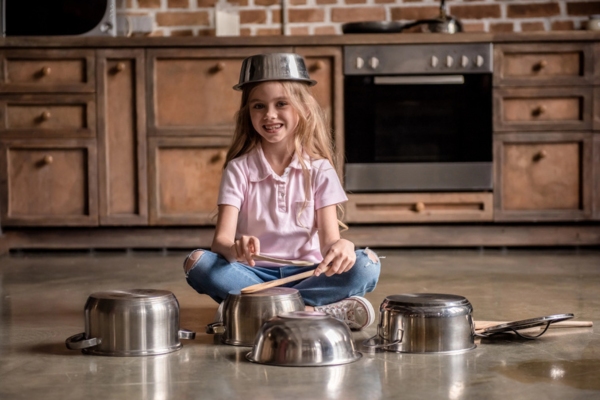 young girl using pots and pans as drums depicting furnace sounds