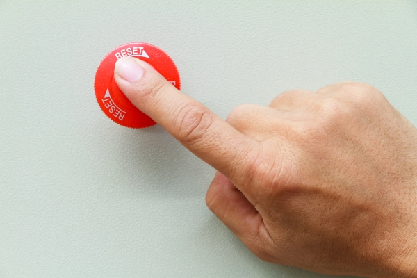 man's hand pressing a red reset button depicting Furnace Reset Button