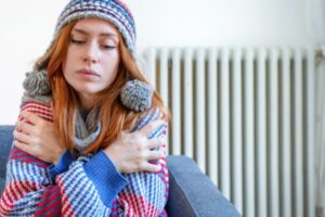 woman feeling cold at home having heating problem