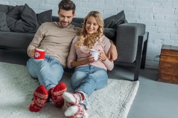couple feeling warm and cozy while drinking coffee and wearing socks indoors