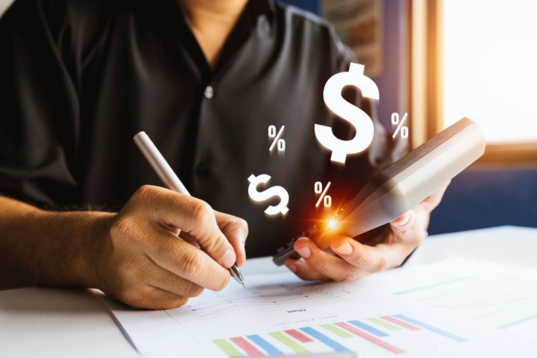 man holding a calculator while writing on paper depicting Calculating Cold-Season Heating Oil Needs