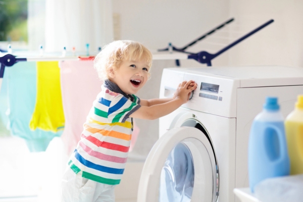 child in laundry room with hands on the propane powered washing machine