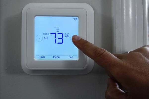homeowner adjusting home temperature using programmable thermostat