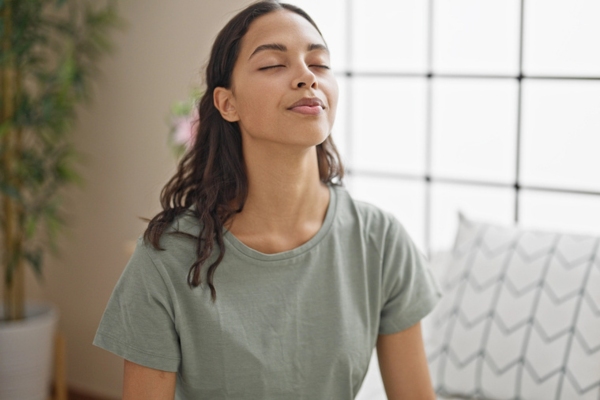 Woman breathing with closed eyes at bedroom depicting better indoor air quality
