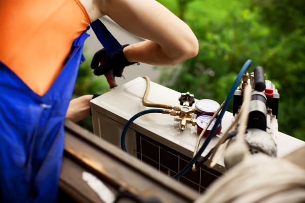 HVAC technician tending to an outdoor air conditioner unit