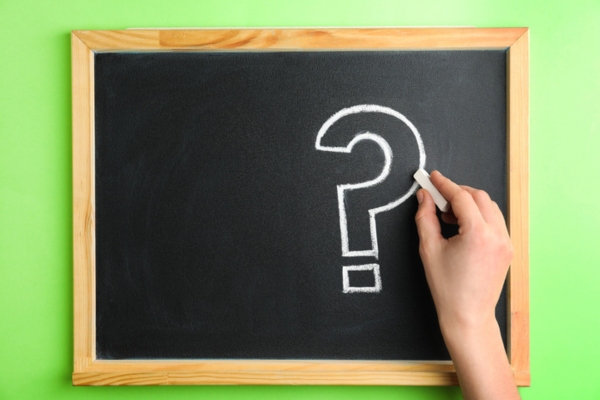woman's hand drawing question mark on a chalkboard depicting Air Conditioning Scams FAQs