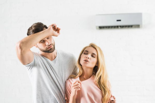 couple wiping sweat and feeling warm due to air conditioner blowing weak air